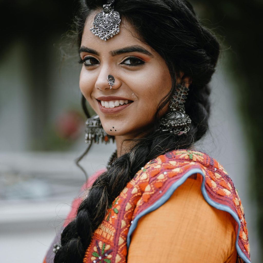 Portrait of a young woman in vibrant traditional Indian attire, smiling outdoors.