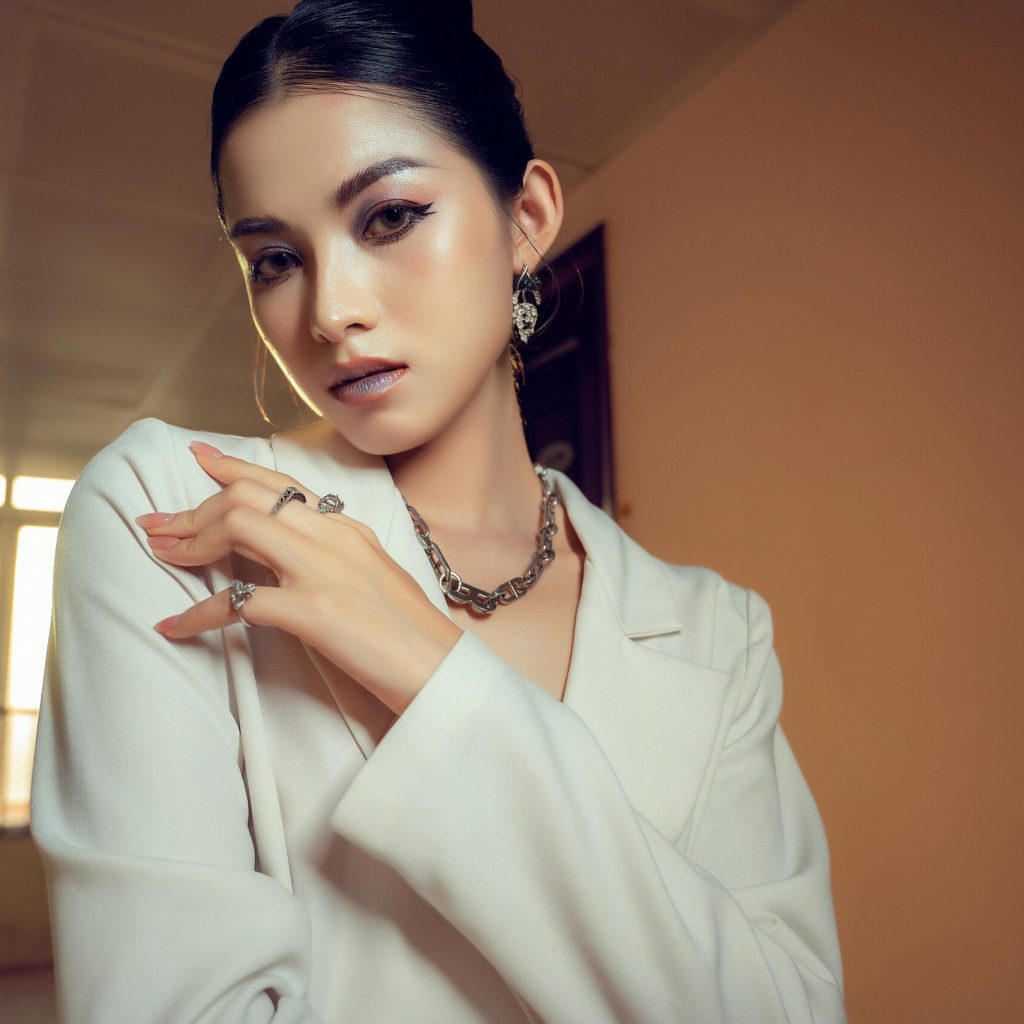 Stylish woman in white attire posing elegantly indoors with soft natural light.