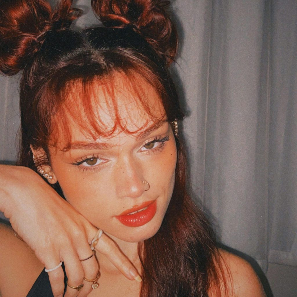 Portrait of a woman with red lips and unique hairstyle posing indoors.