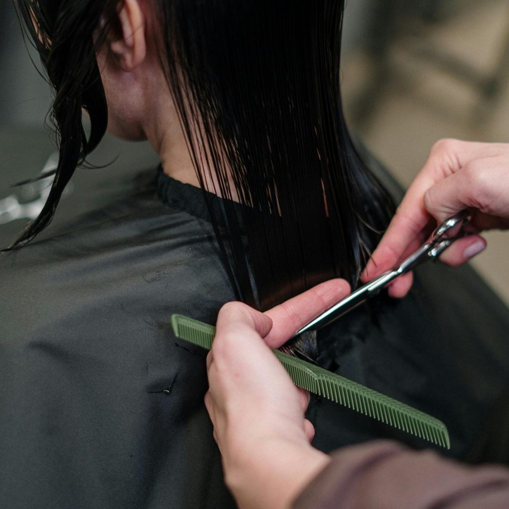 Close-up of a hairstylist cutting a woman's hair in a salon, showcasing precise techniques.