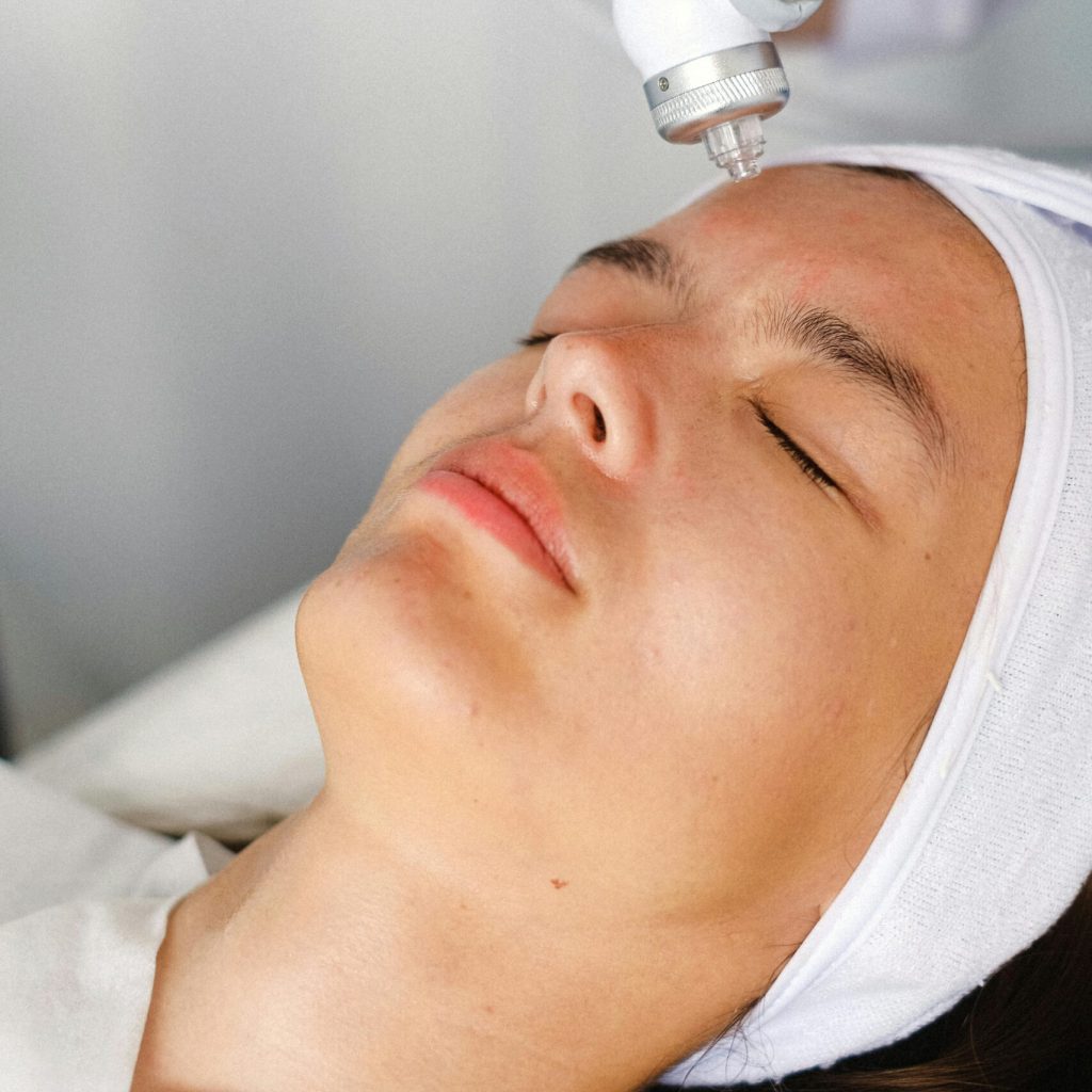 High angle of crop professional cosmetician doing face skin care therapy with laser tool